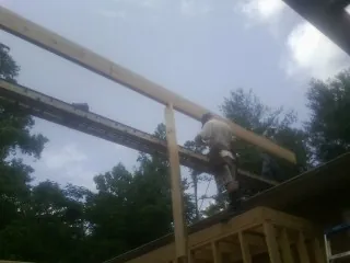 Carpenter setting a ridge beam over a new addition frame — Ice Dam Removal by Roofing Brothers in Renovo