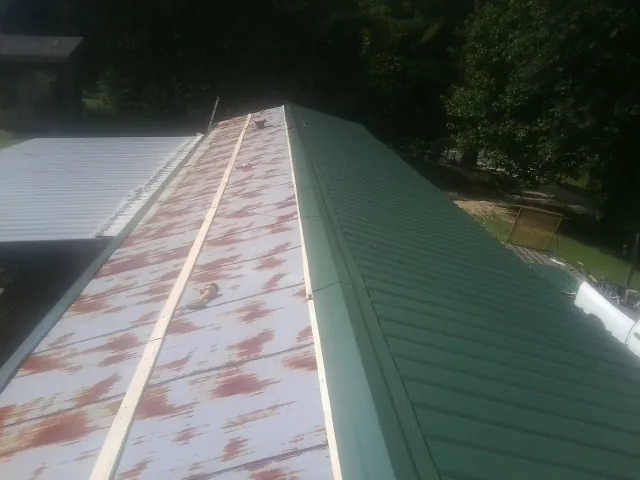 Old rusted panels beside newly installed green metal roofing — Wind Damage Roof Repair by Roofing Brothers in Renovo