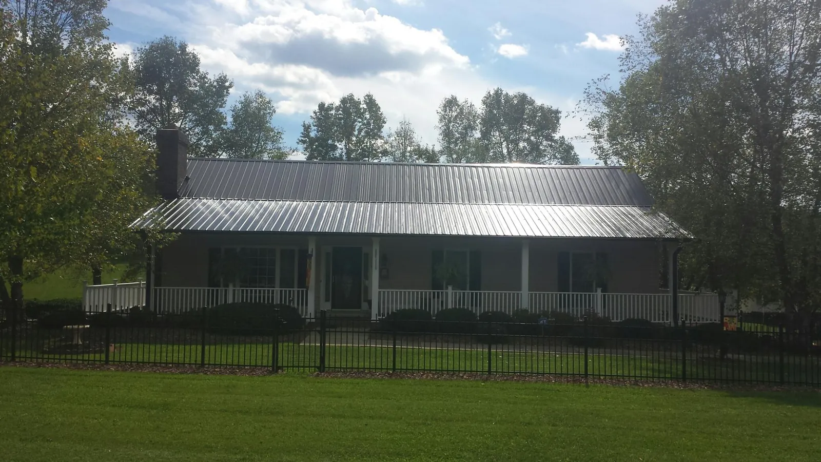 Gray metal roof on a brick ranch with a full width front porch — Gutter Guard Installation work by our crew in Renovo