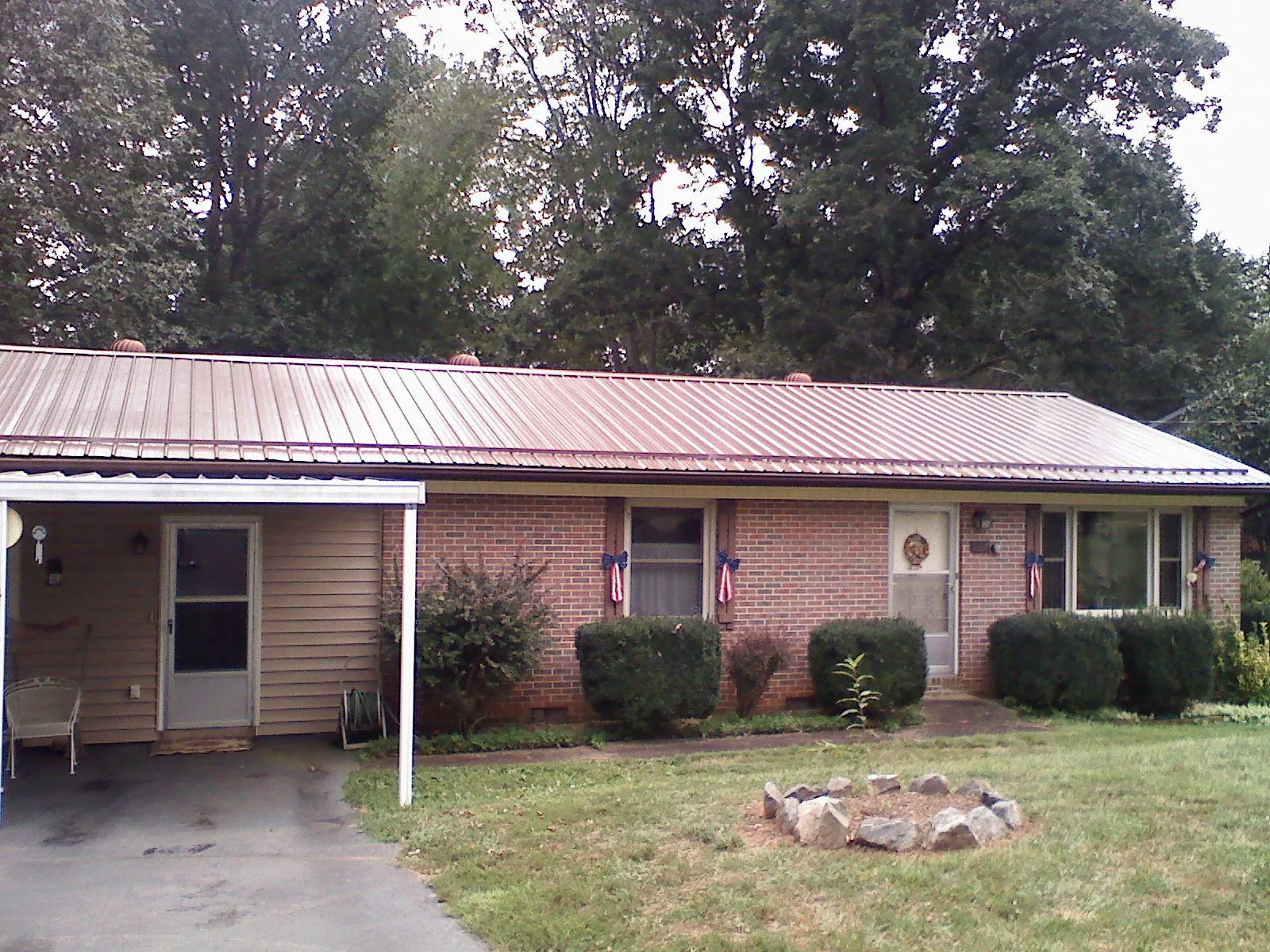 Bronze metal roof and carport on a brick ranch home — Roof Repair work by our crew in Renovo