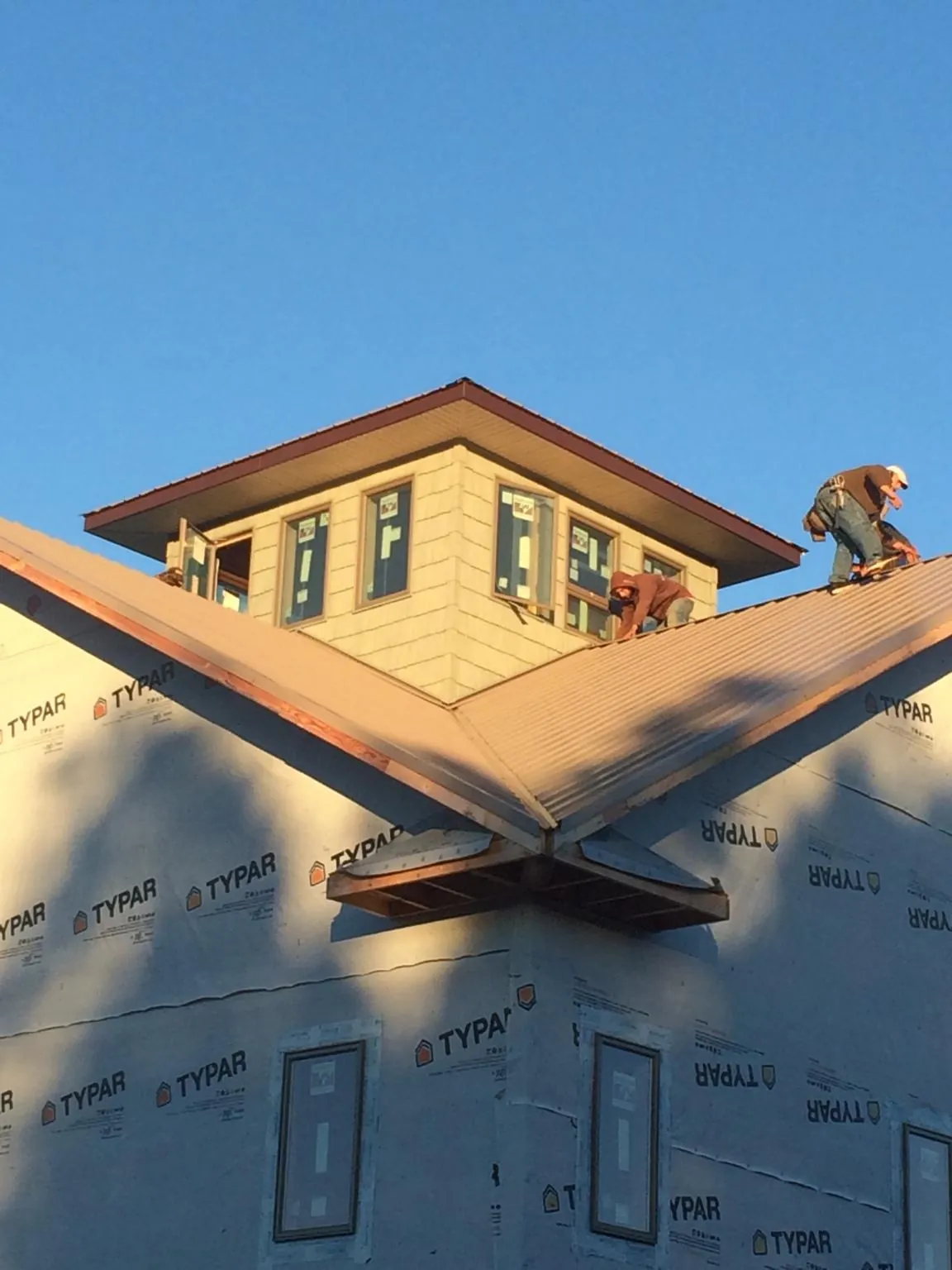 Roofers working around a rooftop cupola on a new metal roof at sunset — Roof Waterproofing in Renovo by Roofing Brothers